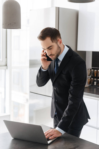 Image of attractive businessman talking on mobile phone while wo - Фото, зображення
