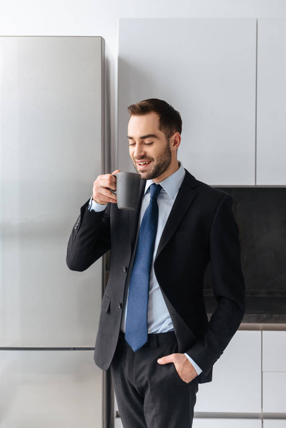Image of positive businessman holding cup with tea while working - Foto, Imagem