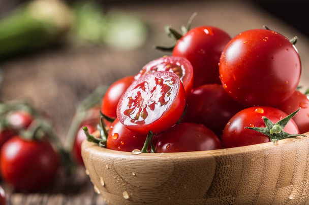 Fresh cherry tomatoes in wooden bowl on old oak table - Zdjęcie, obraz