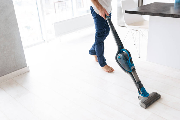 Close up of a man vacuuming the floor - Фото, зображення
