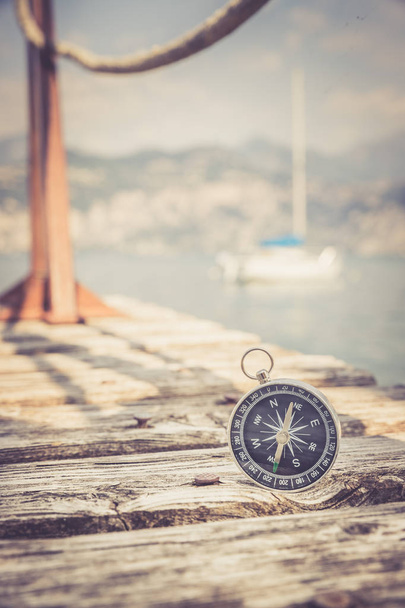 Sailing: nautical compass on wooden dock pier. Sailing boats in  - Zdjęcie, obraz