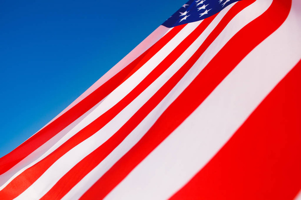 American flag flying in the wind against a blue sky - Zdjęcie, obraz