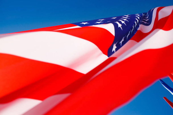 Американский флаг, летящий на ветру против голубого неба
 - Фото, изображение