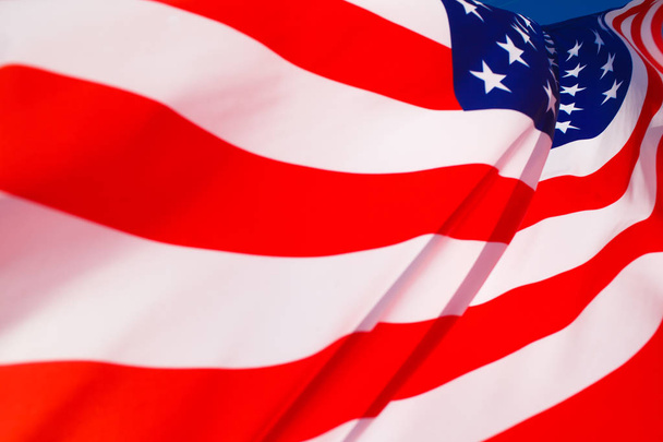 American flag flying in the wind against a blue sky - Zdjęcie, obraz