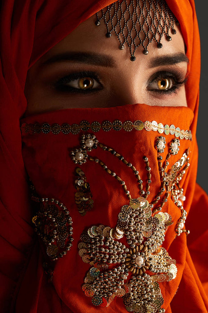 Studio shot of a young charming woman wearing the terracotta hijab decorated with sequins and jewelry. Arabic style. - Fotoğraf, Görsel