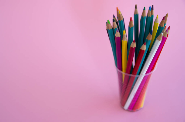 Colored wooden pencils for drawing in a glass stand on a pink ba - Foto, Imagem