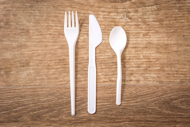 Disposable plastic cutlery on wooden table. Top view.  - Φωτογραφία, εικόνα