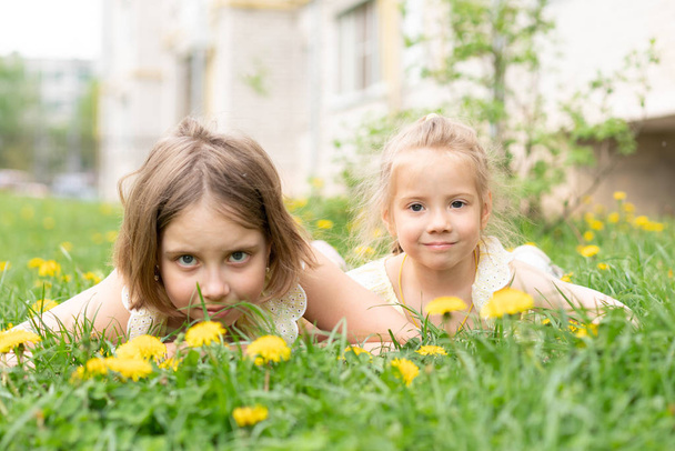zwei Mädchen liegen in gelben Kleidern auf dem grünen Gras - Foto, Bild