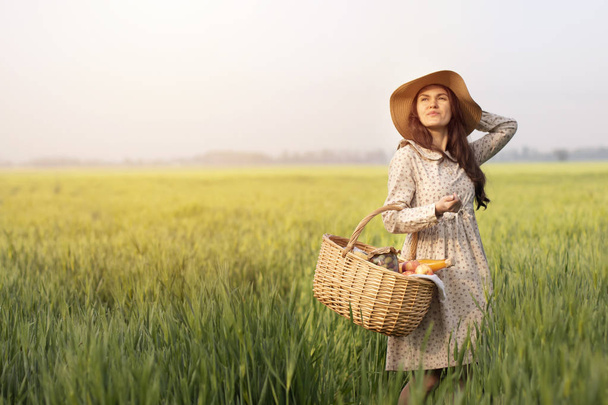 Picnic wicker basket with food on grass in the field. The concept of healthy food, organic natural and fresh products. Grown by a farmer with love - Photo, Image