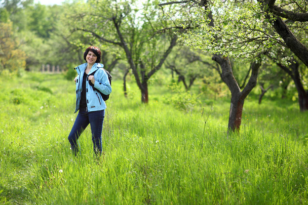 Krásná dospělá žena, která pózá do kamery v jarní zahradě. Dívka se těší rozkvětu jabloní. - Fotografie, Obrázek