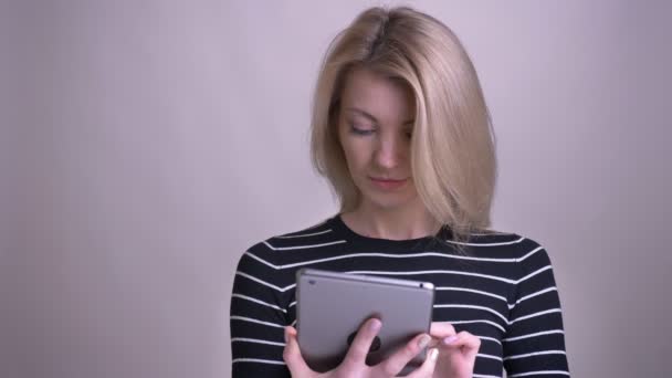 Closeup portrait of adult attractive blonde caucasian female using the tablet and showing green chroma screen to camera with background isolated on white - Video, Çekim