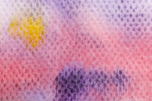 close up view of yellow and purple watercolor paint spills on textured background - Photo, Image
