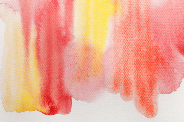 vista de cerca de los derrames de pintura de acuarela de color amarillo pálido y rojo sobre fondo blanco
 - Foto, Imagen