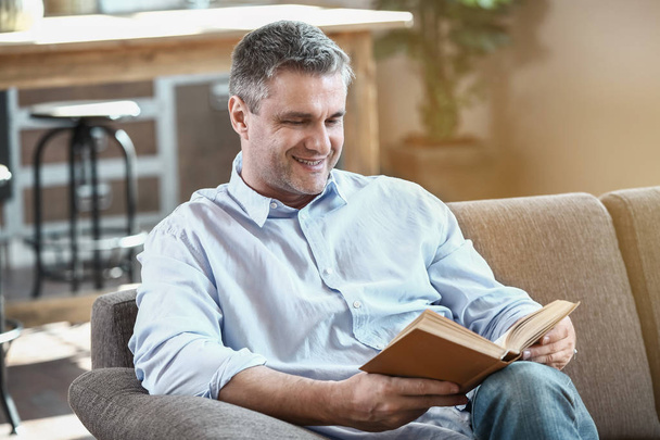 Όμορφος ώριμος άνδρας, διαβάζοντας το βιβλίο στο σπίτι - Φωτογραφία, εικόνα
