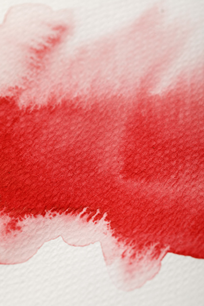 close up view of red watercolor paint wet spill on textured background  - Fotografie, Obrázek