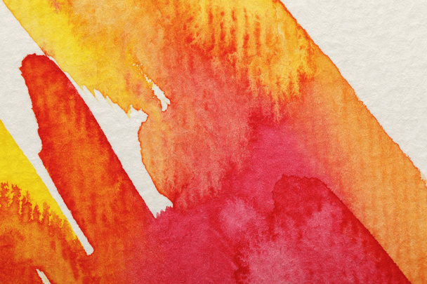 close up view of yellow and red watercolor paint brushstrokes on textured background - Valokuva, kuva