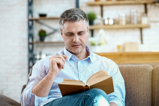 Handsome mature man reading book at home - Foto, Imagem