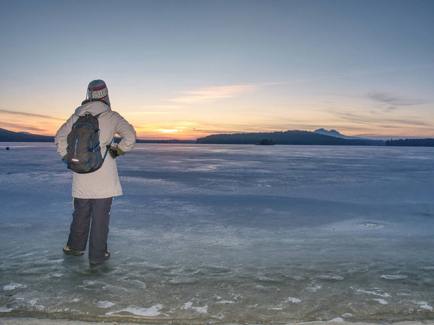 旅行者は凍った海の氷の上に滞在します。バックパックを持つ女性  - 写真・画像