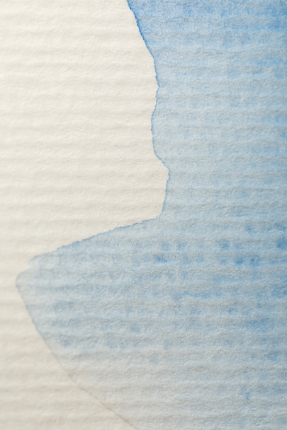 close up view of blue watercolor paint spill on textured paper background with copy space - Valokuva, kuva