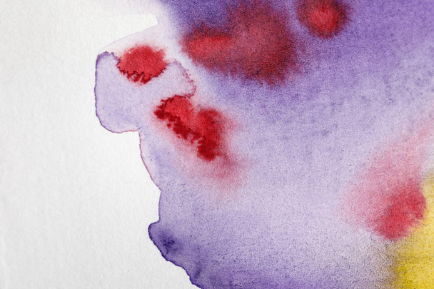 close up view of yellow, purple and red watercolor paint spills on white background - Photo, Image