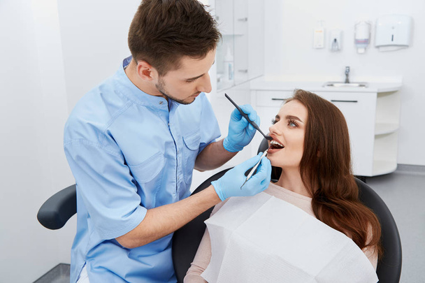 стоматолог, лечащий зубы молодой пациентки в стоматологической клинике
 - Фото, изображение