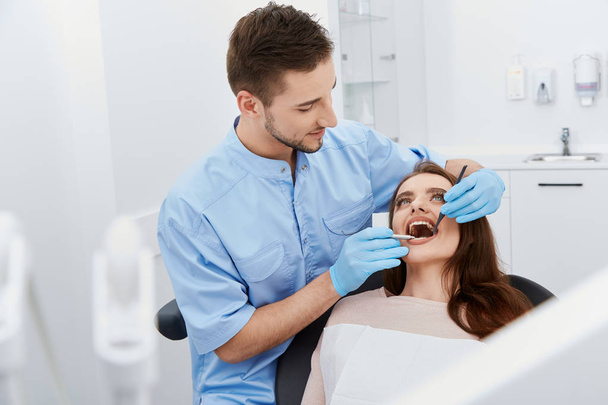 стоматолог лікує молодих жіночих зубів пацієнта в стоматологічній клініці
 - Фото, зображення