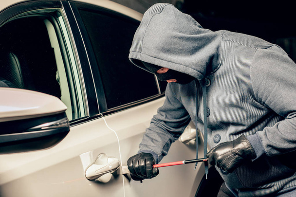 ladrón masculino va a abrir la puerta del coche con una palanca
. - Foto, Imagen
