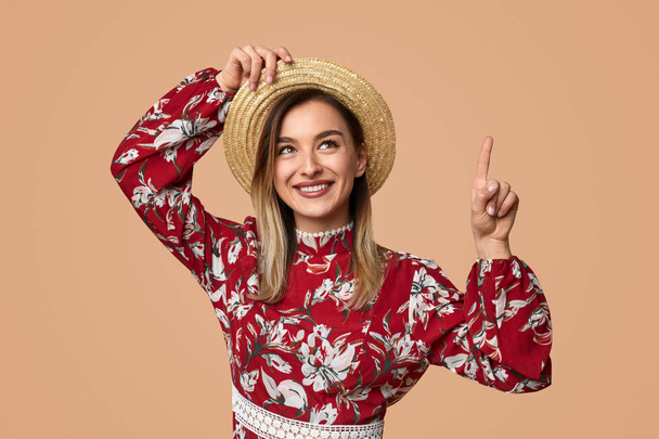 Smiling female in floral dress pointing up - Foto, imagen