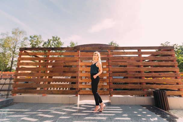 Stylish blonde girl posing near a wooden fence - Valokuva, kuva