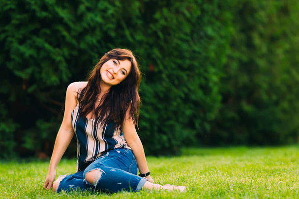 女の子は公園の草の上に座って、笑顔 - 写真・画像
