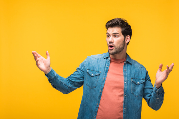 surprised handsome man gesturing isolated on yellow - Φωτογραφία, εικόνα