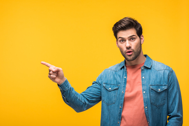 surprised handsome man pointing with finger isolated on yellow - Photo, Image