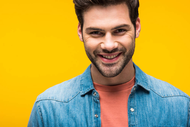 smiling good-looking man looking at camera isolated on yellow - Φωτογραφία, εικόνα