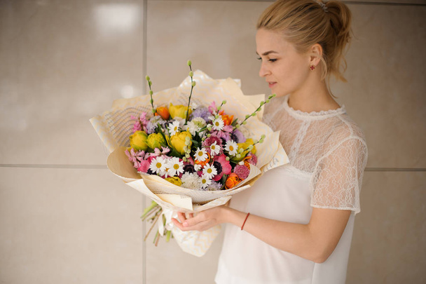 Blond girl holds a beautiful bouquet with daisies - Foto, immagini