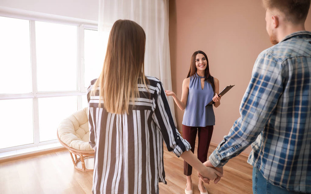 Real estate agent showing young couple a new house - Photo, Image