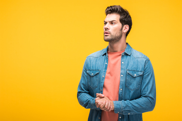 confused handsome man with clenched hands isolated on yellow with copy space - Foto, imagen