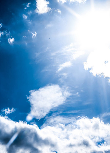 Μπλε φόντο του ουρανού, λευκά σύννεφα και λαμπερό φως του ήλιου - Φωτογραφία, εικόνα