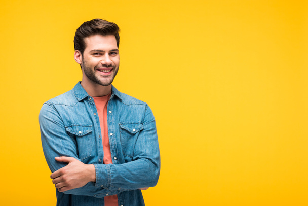 smiling handsome man with crossed arms isolated on yellow with copy space - Photo, Image