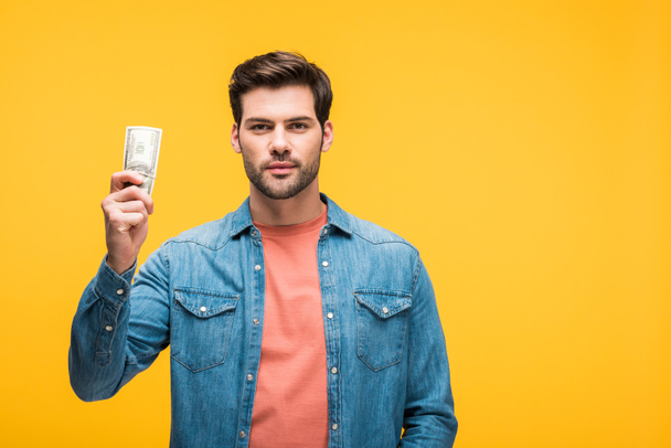 handsome man holding money isolated on yellow with copy space - Photo, Image