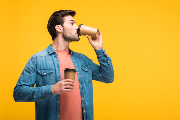 handsome man drinking coffee to go isolated on yellow with copy space - Photo, Image