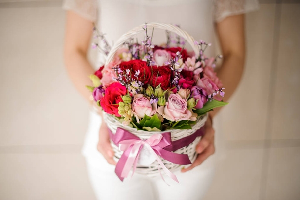 Close up of a woman holding small basket with flowers - Foto, afbeelding