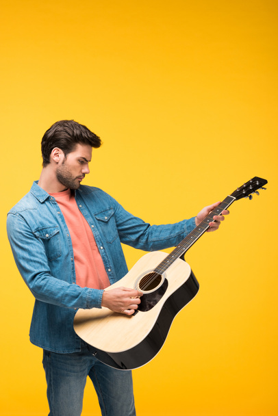 красивий чоловік грає на акустичній гітарі На жовтому
 - Фото, зображення
