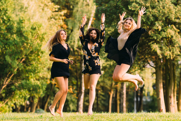 Tytöillä on hauskaa puistossa. hymyilee ja hyppää vastaan b
 - Valokuva, kuva