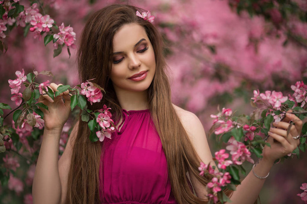 Closeup romantic portrait of young beautiful woman in blossom apple garden with pink flowers - Foto, afbeelding