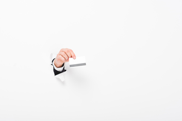 Обрезанный вид человека, держащего кредитную карту из отверстия в стене на белом с копировальным местом
 - Фото, изображение