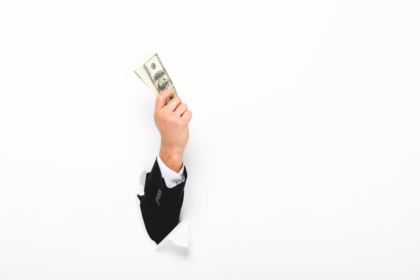 Cropped view of man holding money through hole in paper wall on white with copy space - Photo, Image