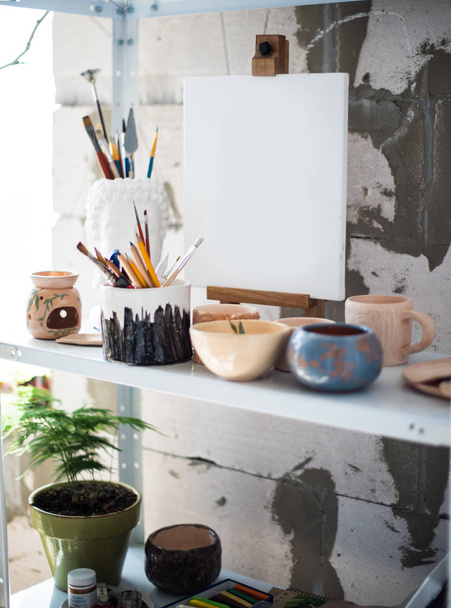 Potloden, canvas en borstels op plank in artistieke Studio - Foto, afbeelding