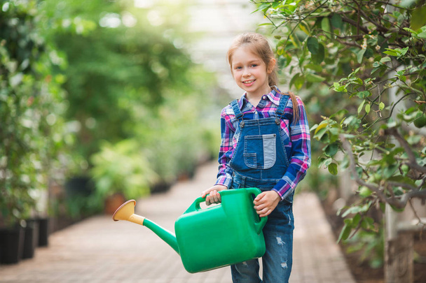 beautiful young girl with a watering can in the hands in the greenhouse garden - Φωτογραφία, εικόνα