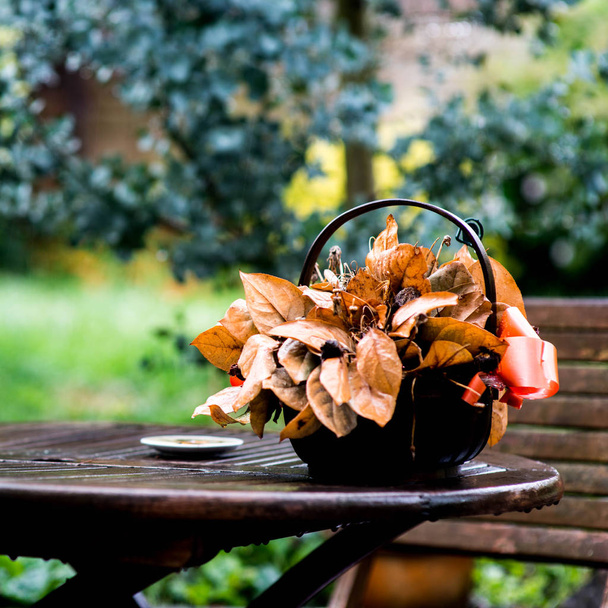 Un panier de fleurs mortes sur une table de jardin
 - Photo, image