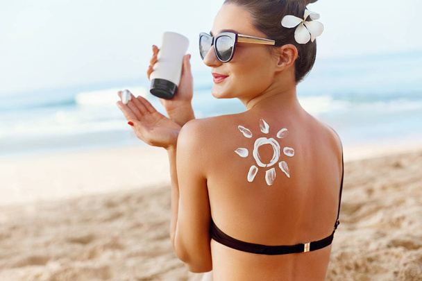 Skin care. Sun protection. Woman apply sun cream. Girl Holding Moisturizing Sunblock. Woman With Suntan Lotion On Beach In Form Of The Sun. Portrait Of Female With  Drawn Sun On A Shoulder. Suncream. - Photo, Image